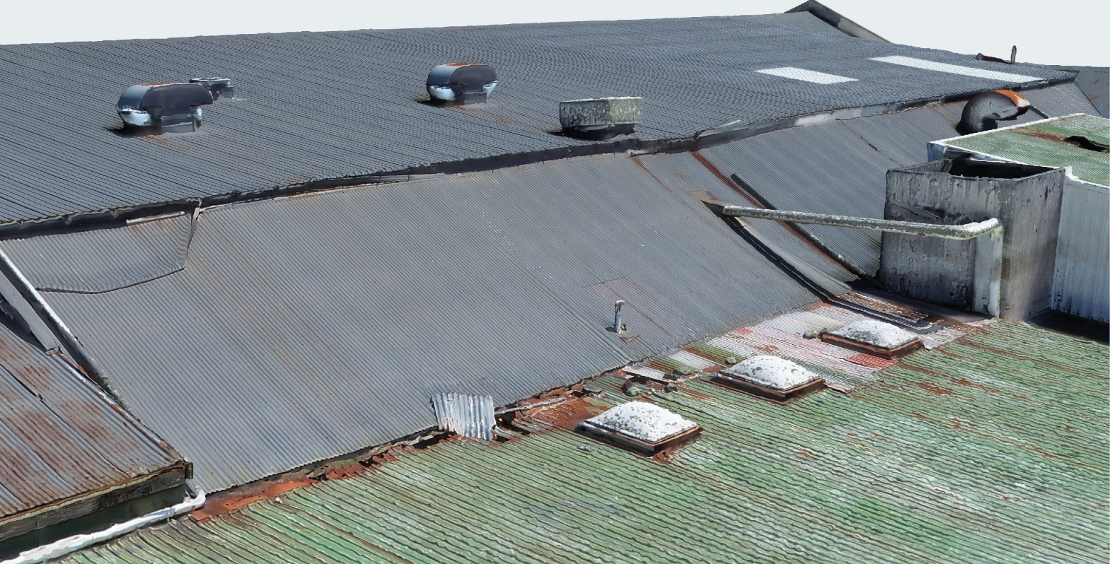 Roofs of the Ōkato cheese factory in the 3D inspection model: corrugated sheets with rust along the laps and around three skylights, patched sheets, lifting flashings at the step between roofs, roof ventilators and an old extract stack with a pipe